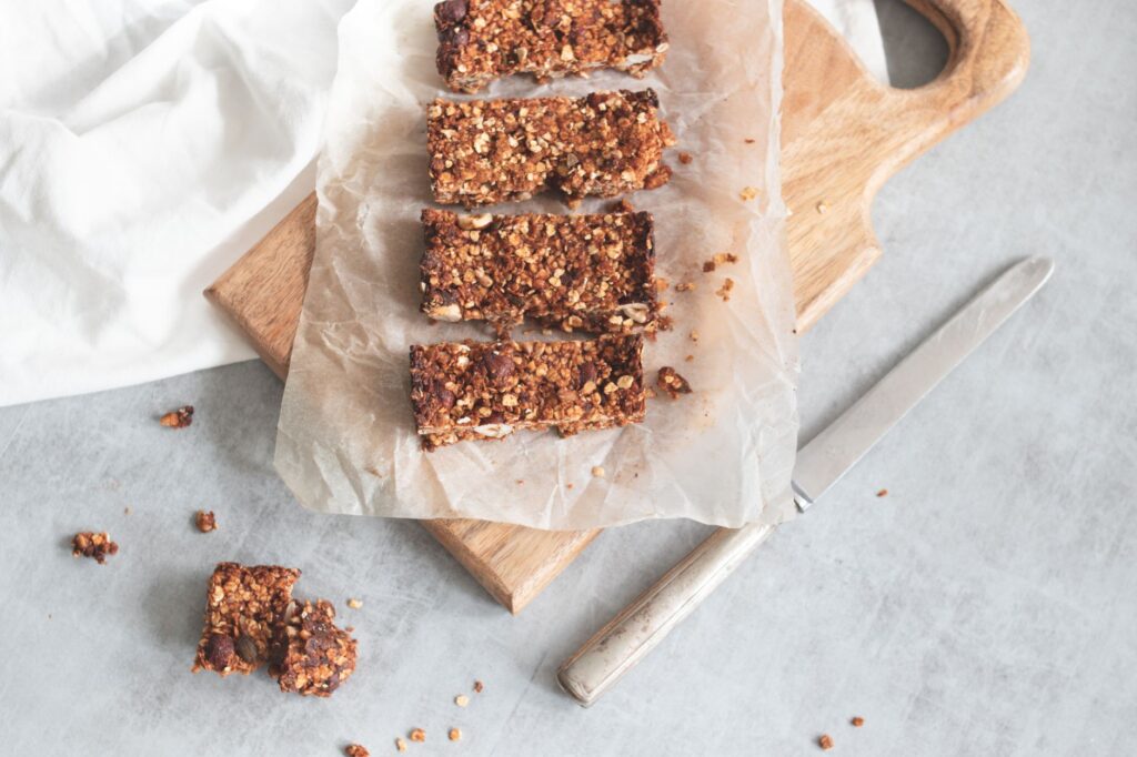 Délicieuses barres granola maison sur une planche en bois, parfaites pour grignoter sainement et préparer des repas.