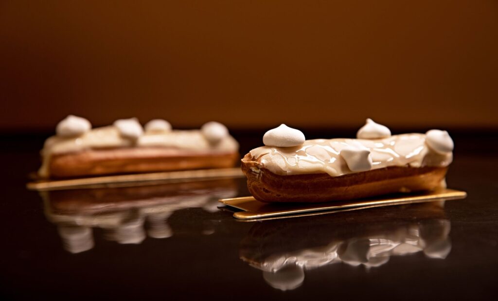 Délicieux éclairs avec glaçage blanc et meringue sur des plateaux dorés, présentés avec style.