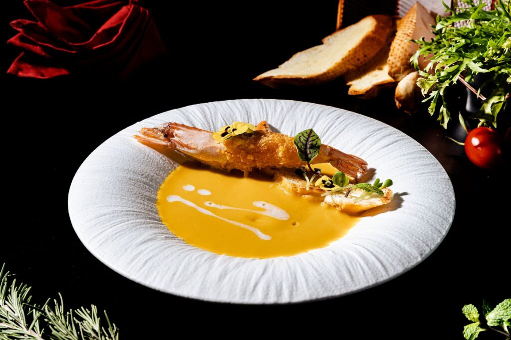 Délicieuse bisque de crevettes gastronomique servie avec des herbes fraîches, parfaite pour une expérience culinaire raffinée.