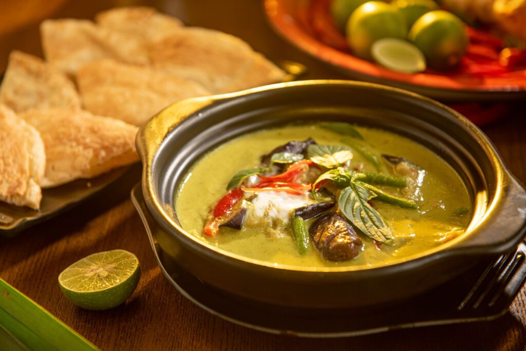 Un curry vert thaï savoureux avec des légumes et des herbes aromatiques dans un élégant bol noir.