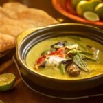 Un curry vert thaï savoureux avec des légumes et des herbes aromatiques dans un élégant bol noir.