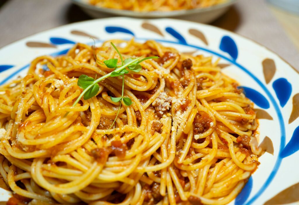 Gros plan de savoureux spaghettis bolognaise garnis d'herbes fraîches sur une assiette décorative.