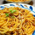 Gros plan de savoureux spaghettis bolognaise garnis d'herbes fraîches sur une assiette décorative.