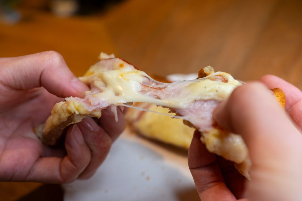 Fromage fondu s'étendant d'un sandwich au fromage grillé chaud en train d'être déchiré, mettant en valeur sa texture gluante.