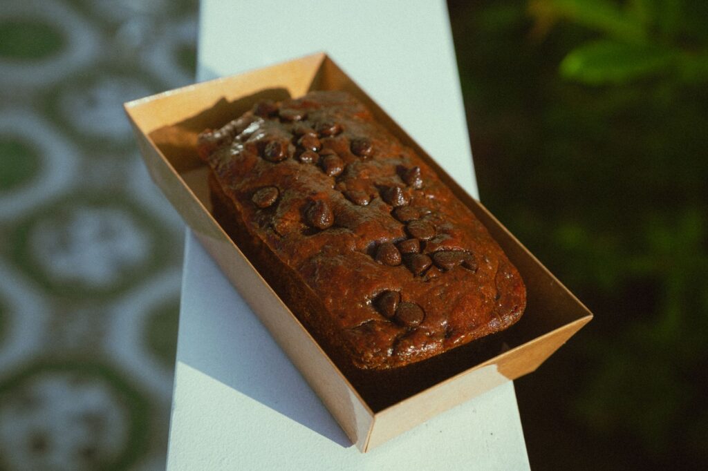 Gâteau aux pépites de chocolat qui met l'eau à la bouche dans une boîte, en extérieur. Parfait pour la photographie culinaire et les amateurs de desserts.