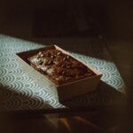 Un riche gâteau au chocolat avec une ambiance vintage, placé sur une table à motifs dans une lumière douce.