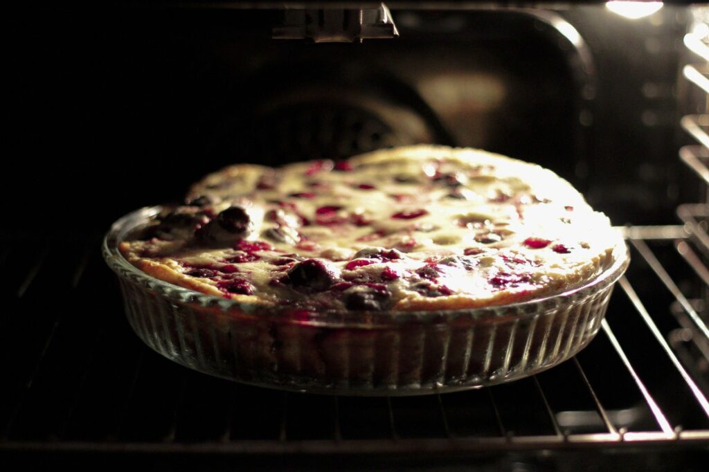 Un clafoutis aux cerises fraîchement cuit dans un plat en verre à l'intérieur d'un four, capturant l'essence des desserts faits maison.