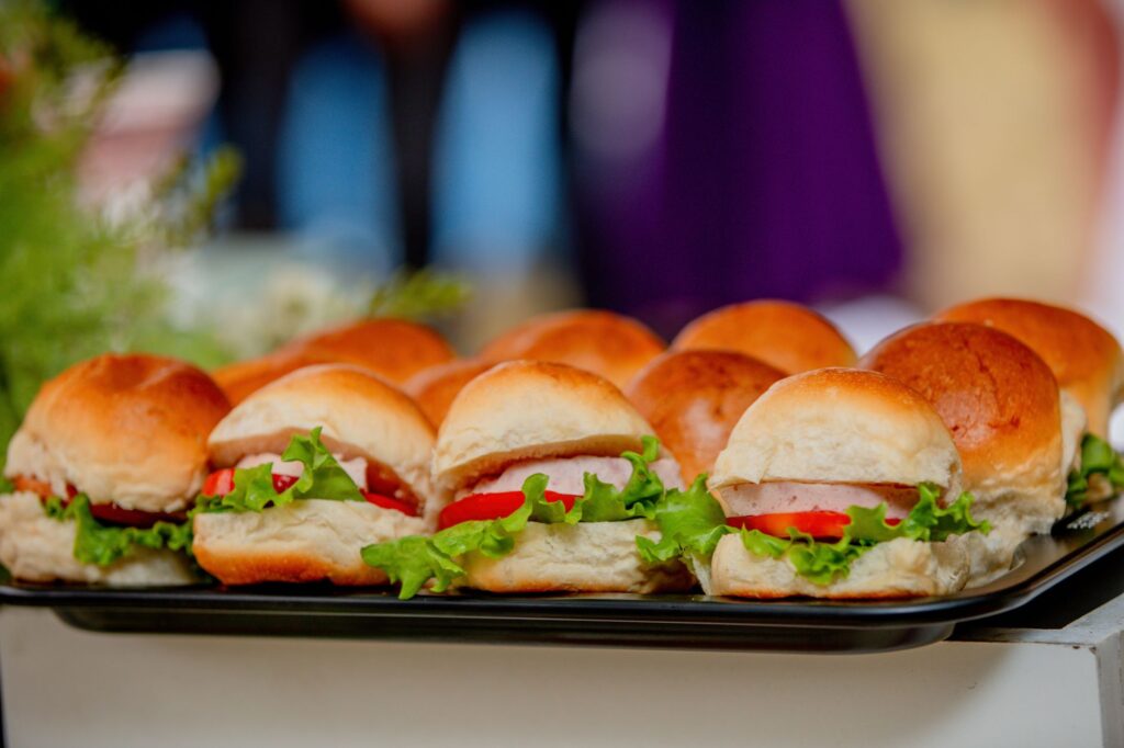 Un gros plan d'un plateau avec des mini sandwiches frais comprenant de la laitue, des tomates et des petits pains.