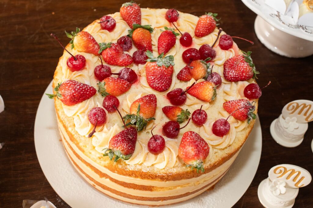 Un gâteau à plusieurs couches irrésistible garni de fraises et de cerises fraîches, parfait pour les célébrations.
