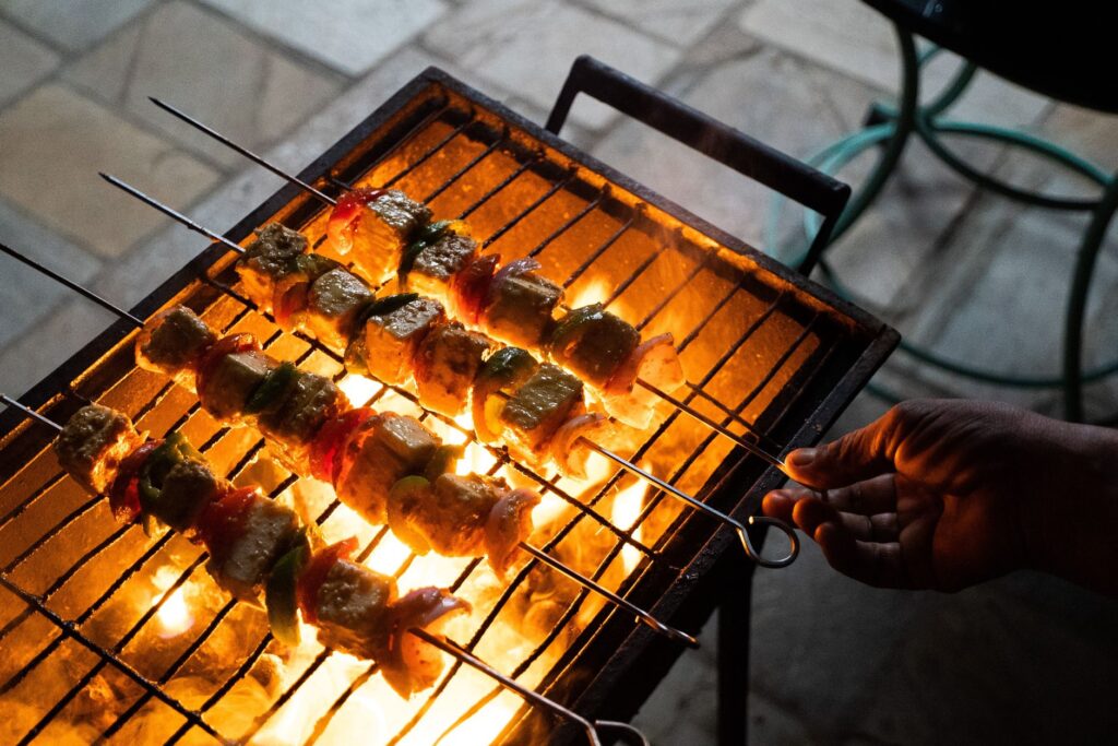 Gros plan de brochettes colorées cuisant sur des flammes nues, capturant l'ambiance d'un barbecue en plein air.