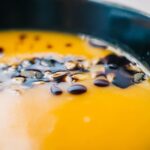 Gros plan appétissant d'une soupe crémeuse à la citrouille garnie dans un bol noir.