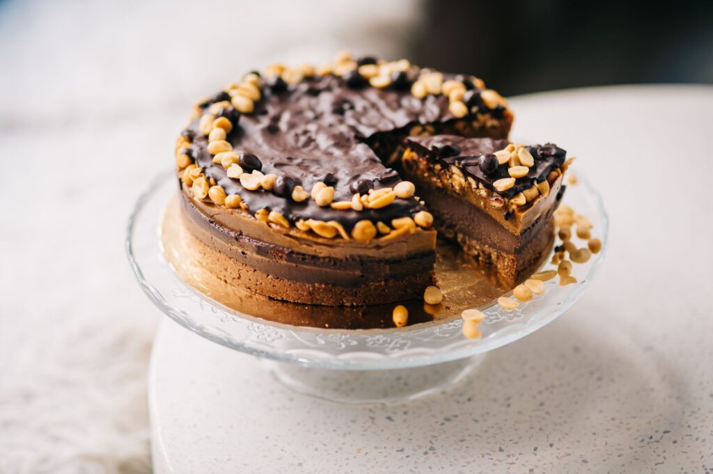 Un riche gâteau au chocolat garni de noix sur un support en verre, invitant et délicieux.