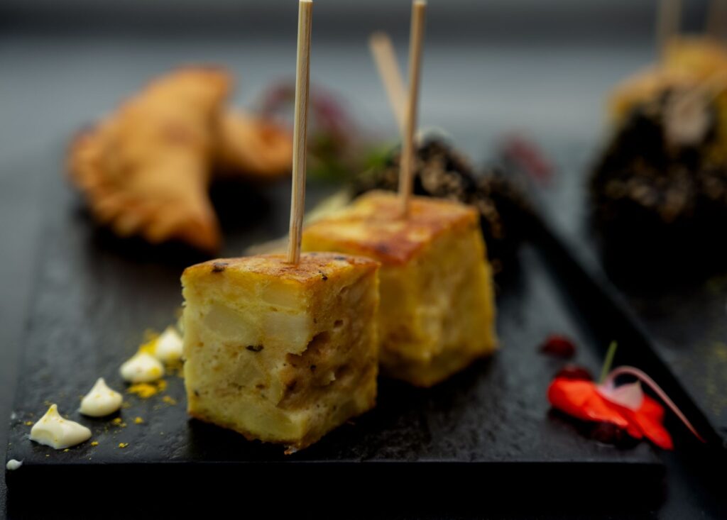 Des tapas argentines alléchantes sur une assiette en ardoise avec une garniture décorative, parfait pour les amateurs de gastronomie.