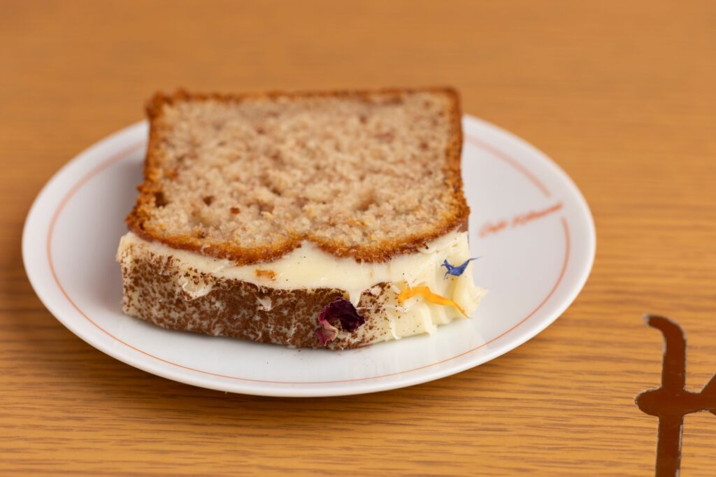 Gros plan sur une part de gâteau fait maison avec glaçage crémeux sur une assiette blanche.