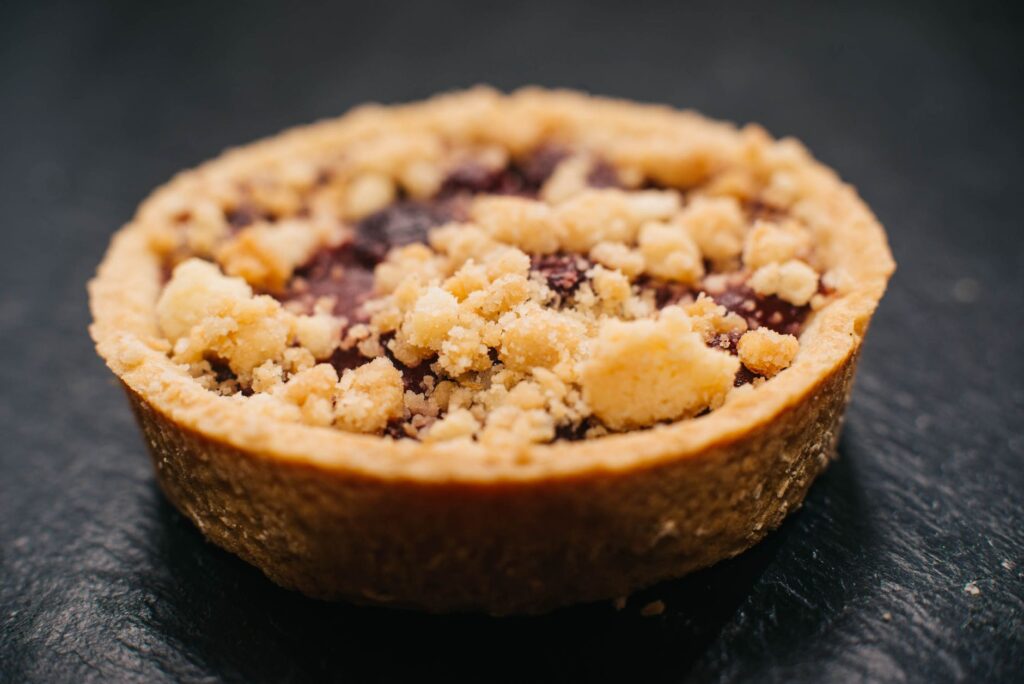 Délicieuse tarte aux baies avec un crumble sur le dessus, présentée avec un flou doux, parfaite pour la photographie de desserts.