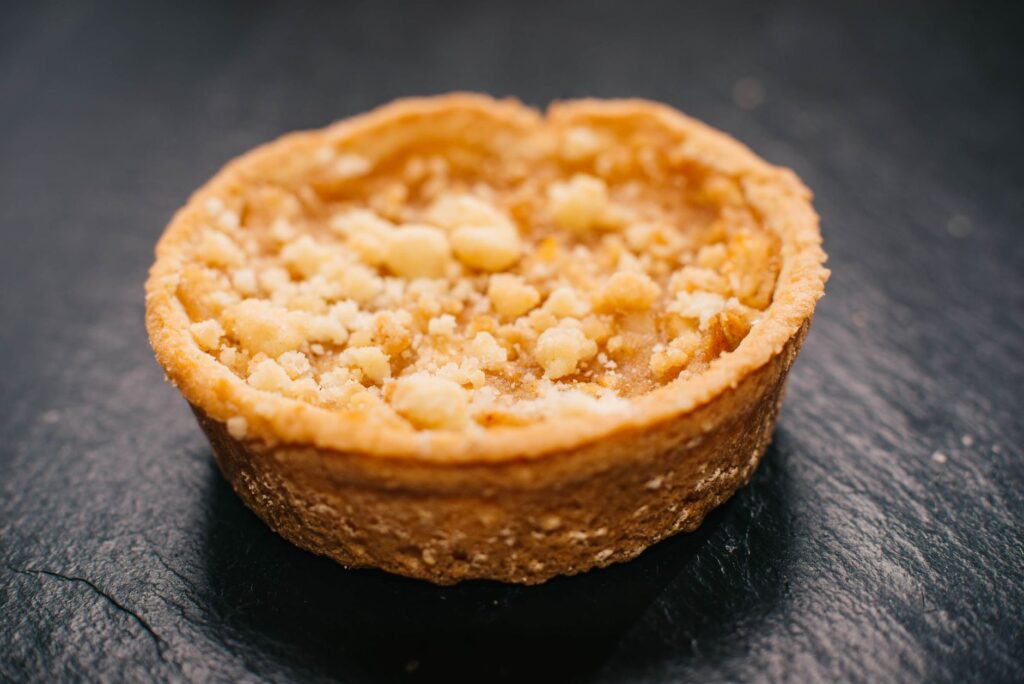 Une tarte aux pommes crumble appétissante sur un fond de ardoise sombre.