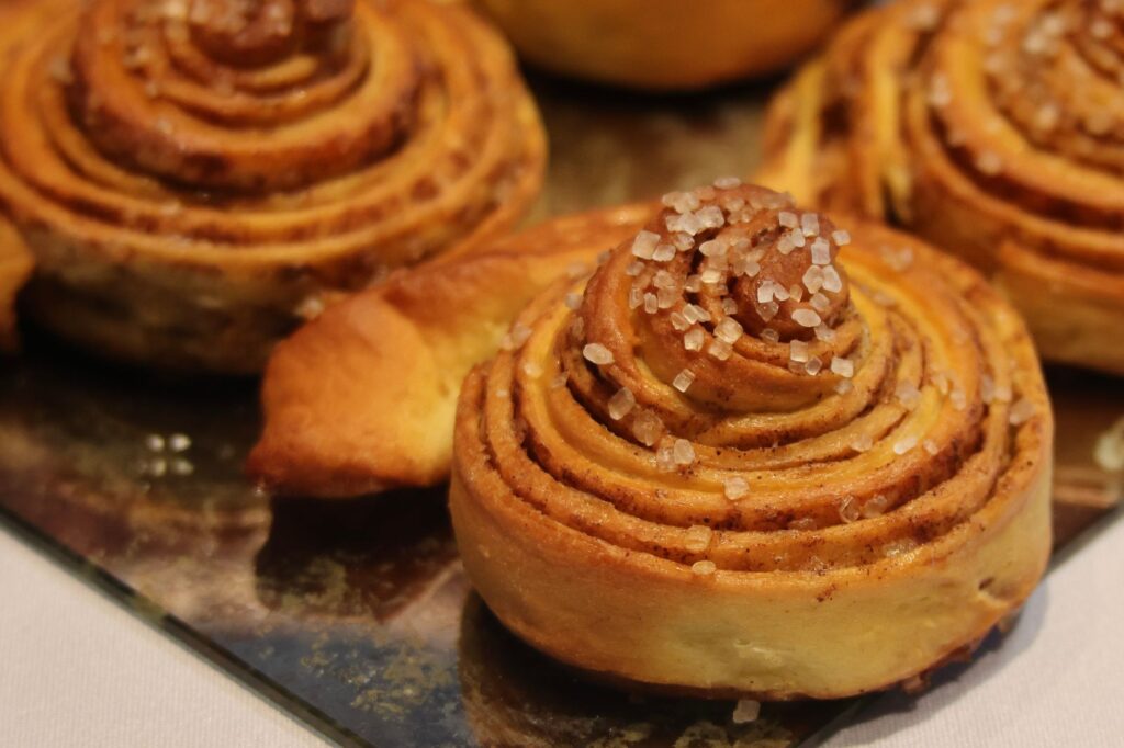 Gros plan sur des brioches à la cannelle fraîchement cuites, recouvertes de cristaux de sucre, idéales pour le petit-déjeuner ou le goûter.