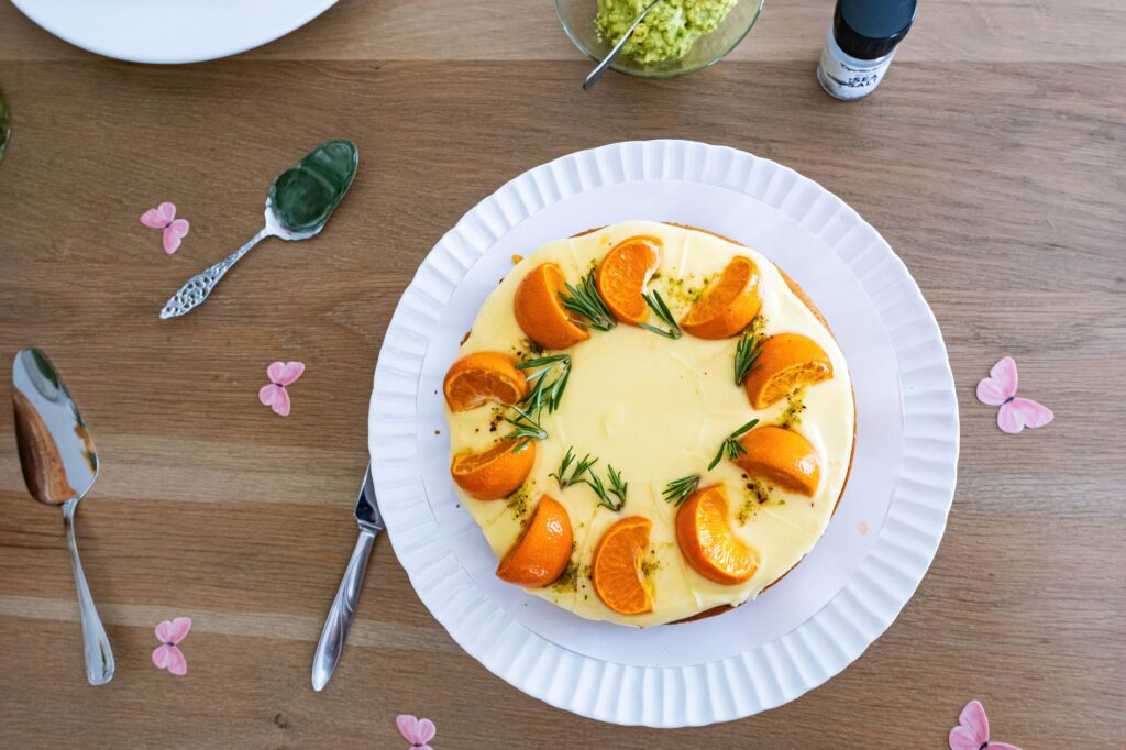Délicieux gâteau à l'orange et au romarin présenté sur une table en bois ornée de fleurs.