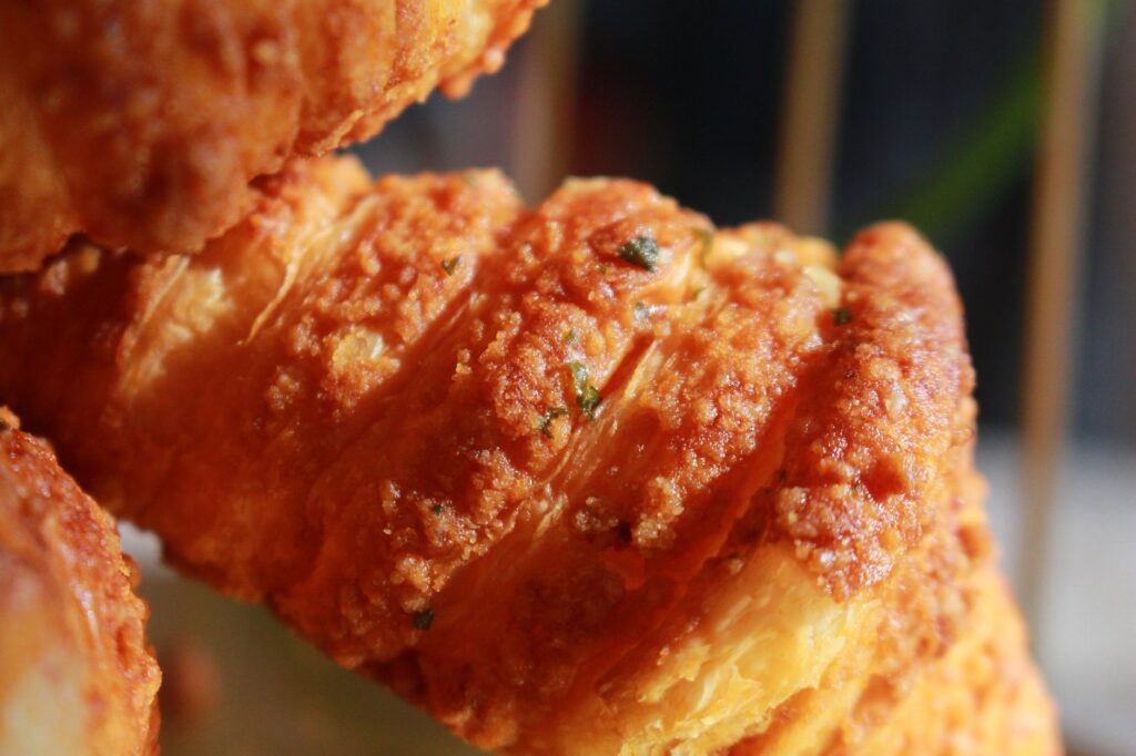 Gros plan détaillé d'un croissant feuilleté, doré et croustillant.