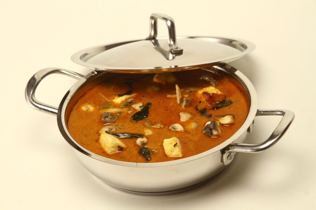 Un curry indien alléchant servi dans une casserole en acier inoxydable brillant, parfait pour la photographie culinaire et les promotions gastronomiques.