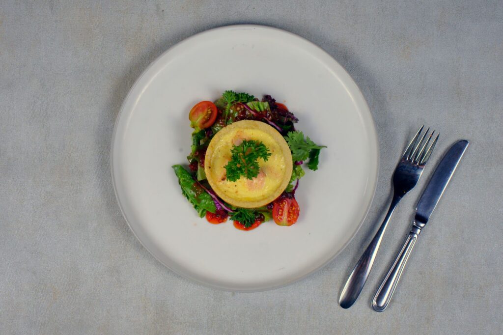 Vue du dessus d'une salade vibrante avec quiche et tomates cerises sur une assiette blanche.