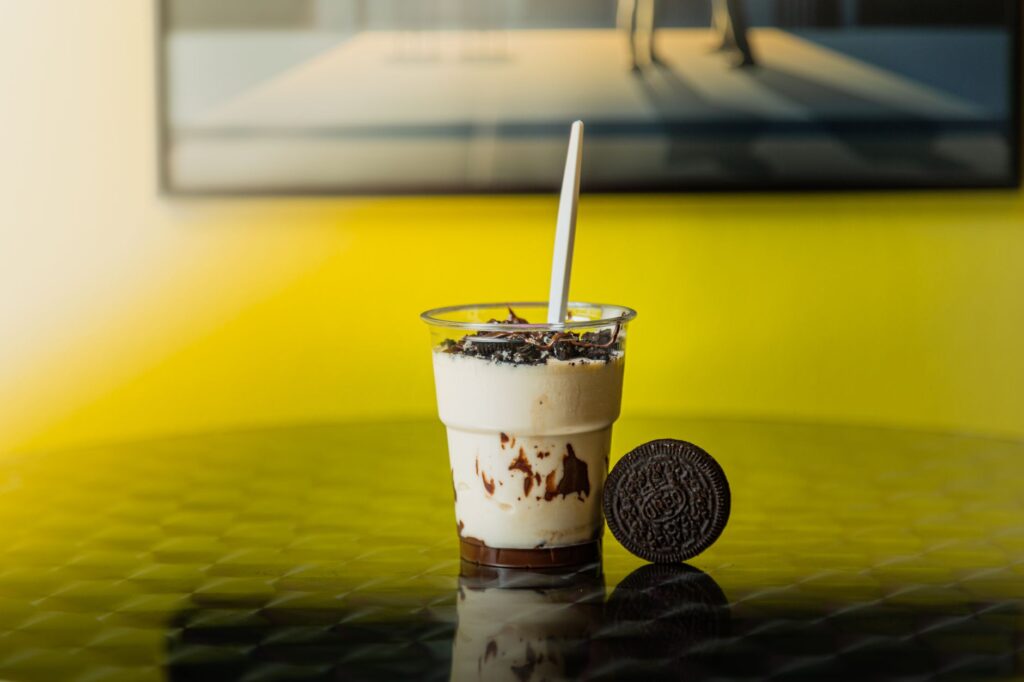 Milkshake Oreo crémeux sur une surface réfléchissante avec un fond jaune. Visuel de douce délicatesse parfait.