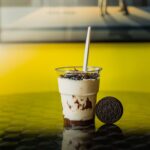 Milkshake Oreo crémeux sur une surface réfléchissante avec un fond jaune. Visuel de douce délicatesse parfait.