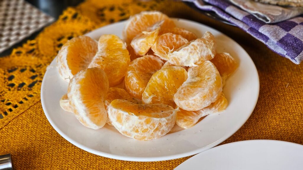 Gros plan sur des tranches de mandarine juteuses disposées sur une assiette blanche, capturant un aspect frais et éclatant.