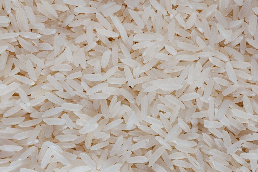 Vue détaillée de grains de riz blanc non cuits, mettant en valeur leur texture et leur motif.
