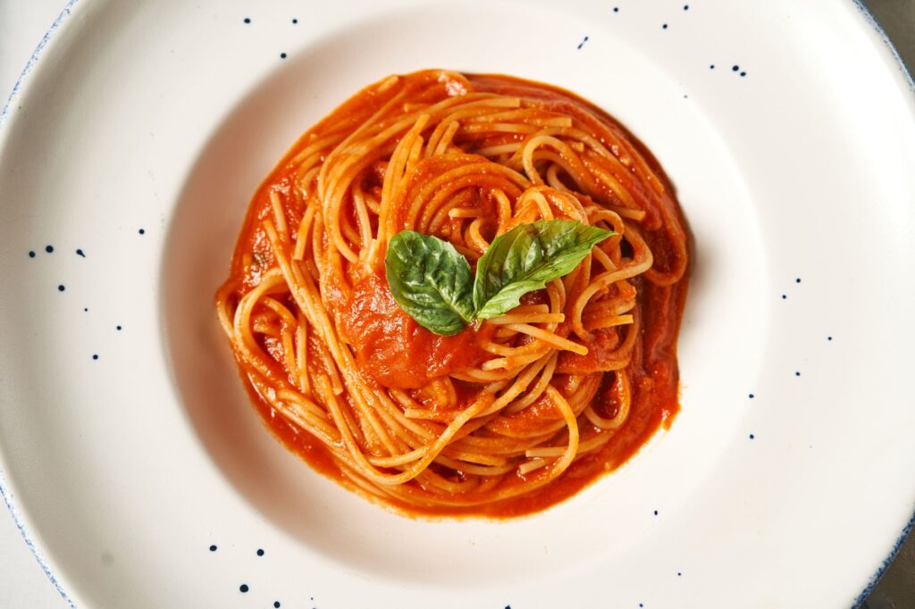 Vue de dessus d'une assiette de spaghettis avec une riche sauce tomate et une garniture de basilic frais.