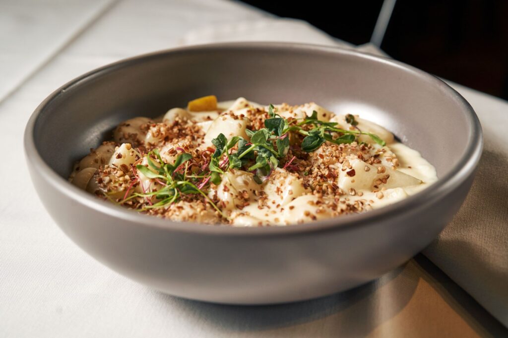 Un bol de gnocchis nappés de sauce à la crème et d'herbes fraîches.