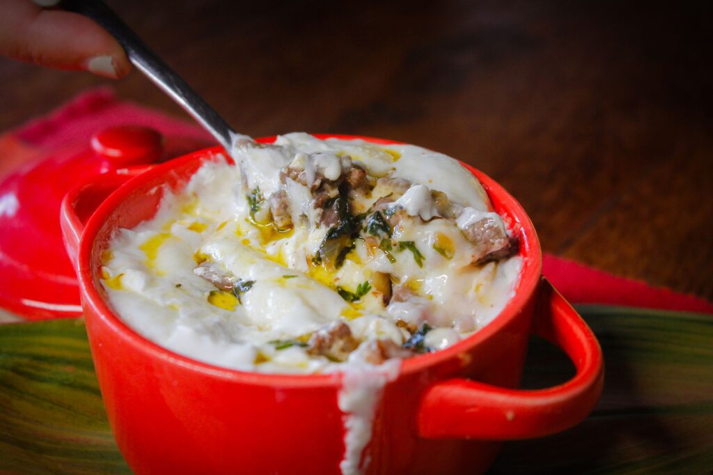 Savourez ce gratin de fromage crémeux aux herbes, servi chaud dans une cocotte rouge éclatante.