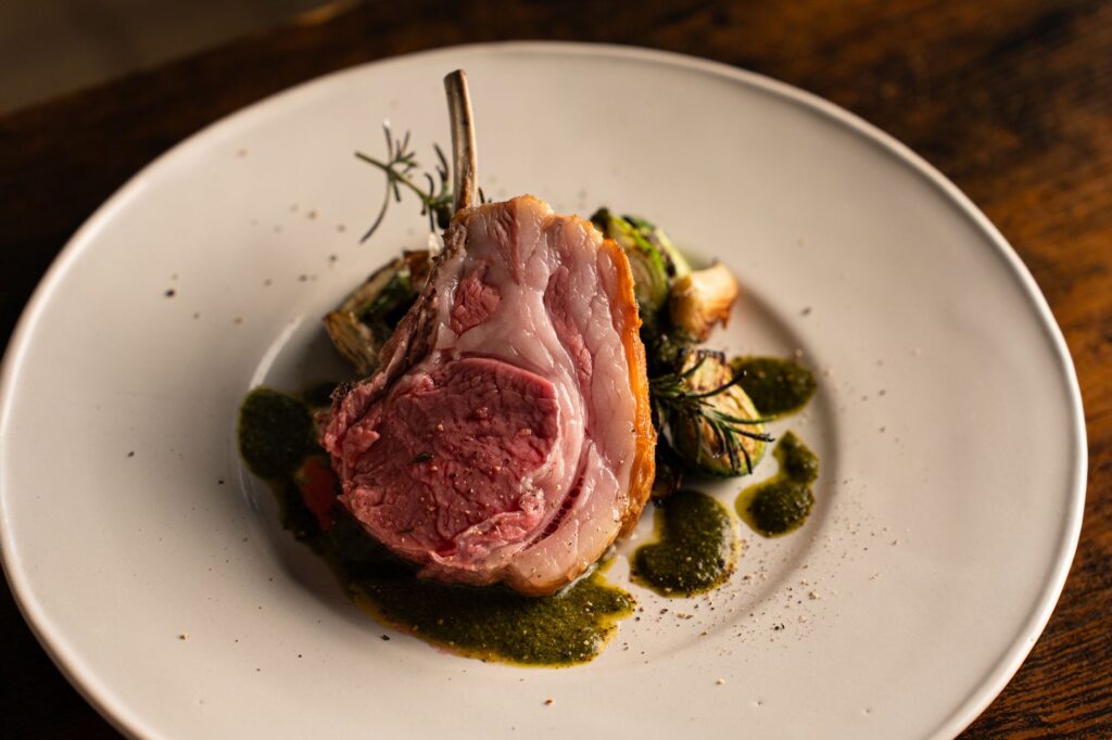Délicieuse côtelette d'agneau gourmet servie avec une sauce aux herbes dans un cadre de haute gastronomie à Tokyo.