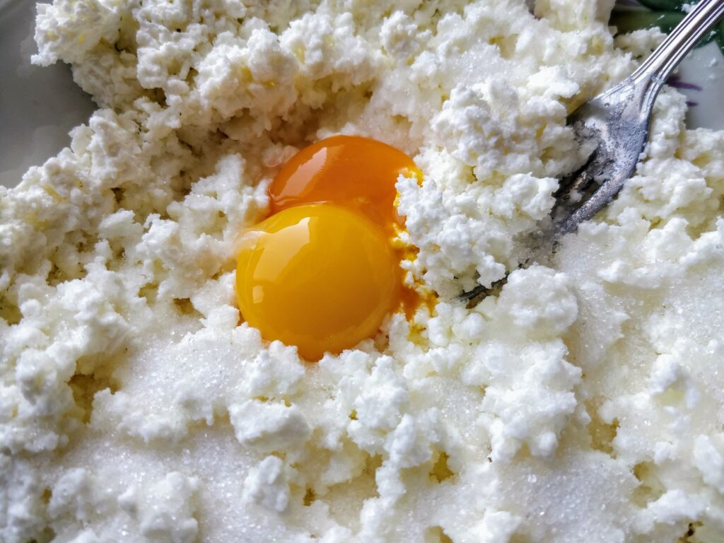 Gros plan sur de la ricotta fraîche mélangée à des jaunes d'œufs crus, prête à être cuite.
