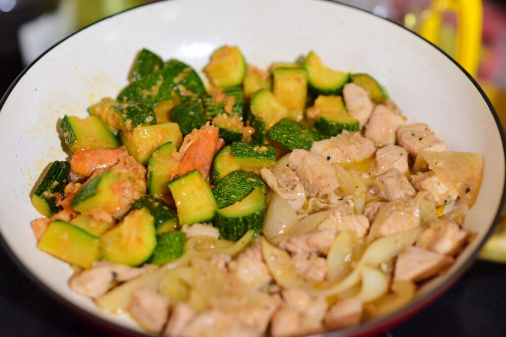 Mélange de poulet sauté et de courgette dans une poêle pour un repas sain.