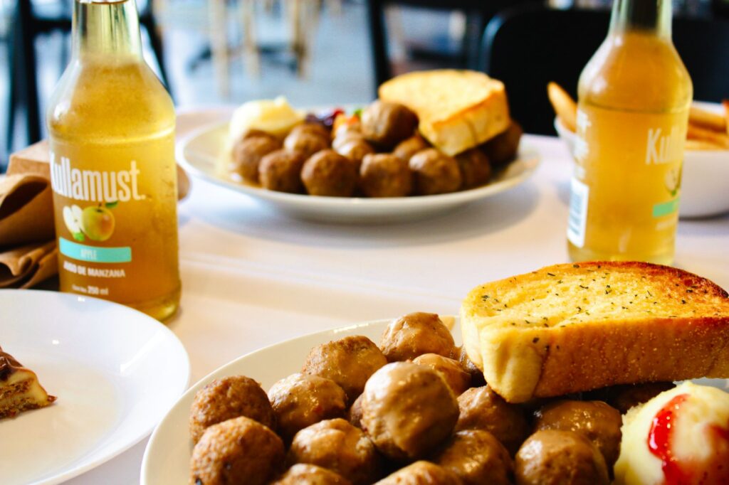 Assiette de boulettes de viande accompagnée de pain à l'ail et de jus de pomme, dans un cadre intérieur moderne.