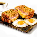 Savourez un Croque Monsieur croustillant accompagné d'œufs au plat et de café.