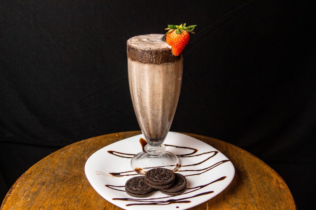 Savourez un milkshake au chocolat crémeux garni d'une fraise fraîche et servi avec des biscuits.