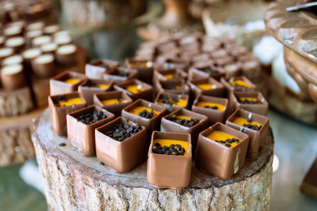 Gros plan sur des cubes de chocolat décoratifs aux riches garnitures, présentés sur une surface en bois rustique au Brésil.