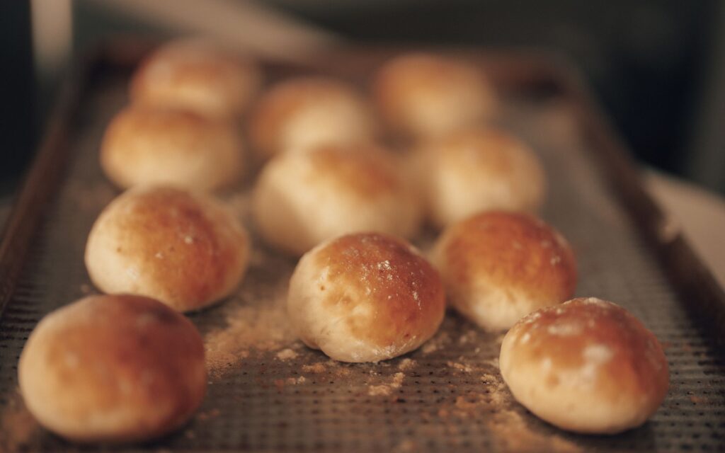 Gros plan sur de petits pains fraîchement cuits sur une plaque de cuisson, chauds et dorés.