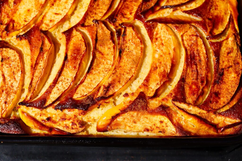 Gros plan délicieux d'un gâteau aux pommes et à la cannelle fraîchement sorti du four, avec des tranches dorées à souhait.