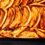 Gros plan délicieux d'un gâteau aux pommes et à la cannelle fraîchement sorti du four, avec des tranches dorées à souhait.
