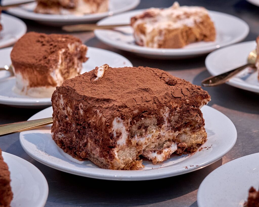 Gros plan sur un délicieux tiramisu présenté sur une assiette blanche, saupoudré de cacao.