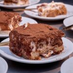 Gros plan sur un délicieux tiramisu présenté sur une assiette blanche, saupoudré de cacao.