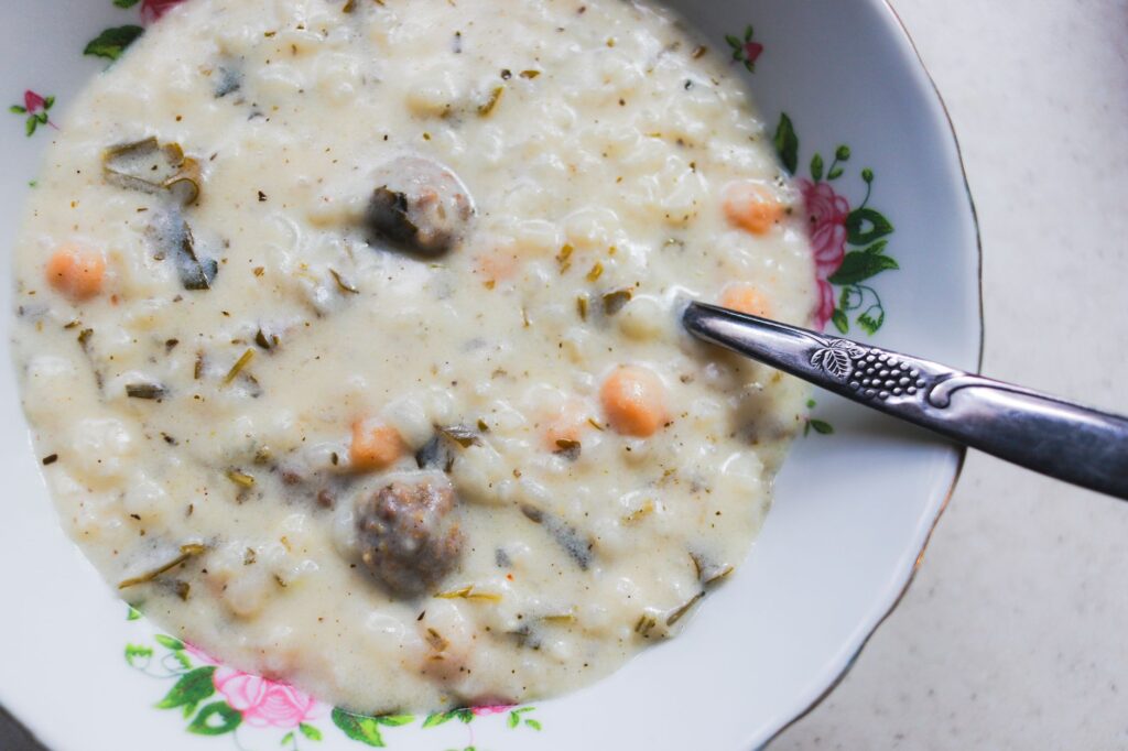 Délicieuse soupe crémeuse aux boulettes de viande, servie dans un bol à motifs floraux avec une cuillère.
