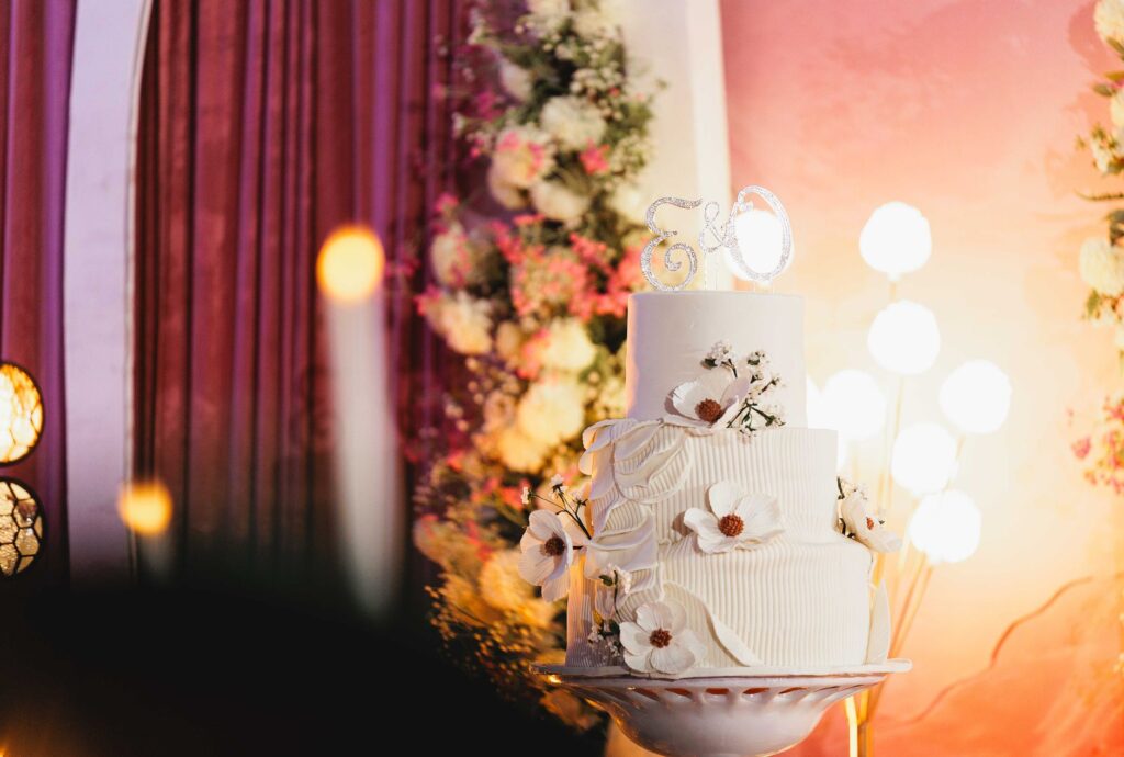 Magnifique gâteau de mariage blanc orné de délicores décorations florales et d'un topper '50', parfait pour une célébration d'anniversaire doré.