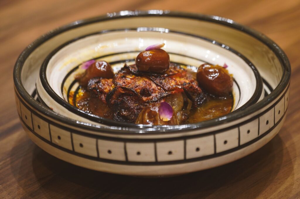 Délicieux tajine marocain aux dattes servi dans un bol artisanal, mettant en valeur les saveurs vibrantes d'Essaouira, au Maroc.