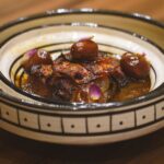 Délicieux tajine marocain aux dattes servi dans un bol artisanal, mettant en valeur les saveurs vibrantes d'Essaouira, au Maroc.