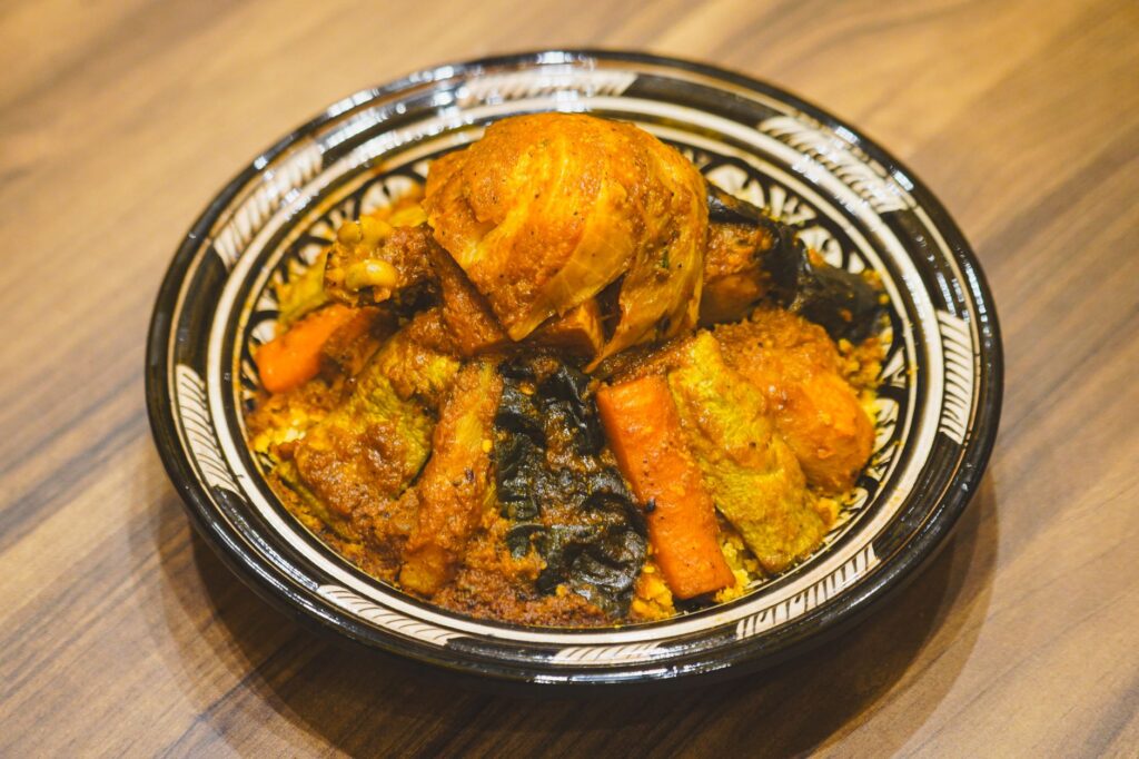 Savourez un copieux couscous marocain au poulet et aux légumes assaisonnés, un plat idéal pour les amateurs de cuisine du monde.