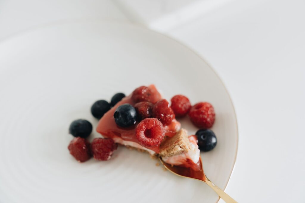 Gros plan sur une part de cheesecake avec des framboises et des myrtilles fraîches dans une assiette.